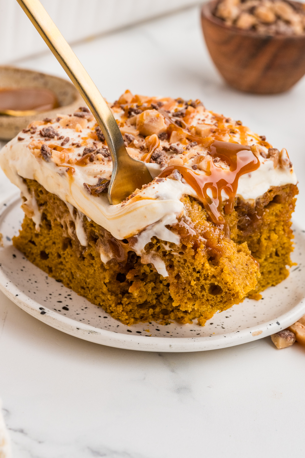 Fork lifting a bite from a slice of cake on a plate.