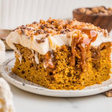 A slice of Pumpkin Poke Cake on a plate missing a bite.