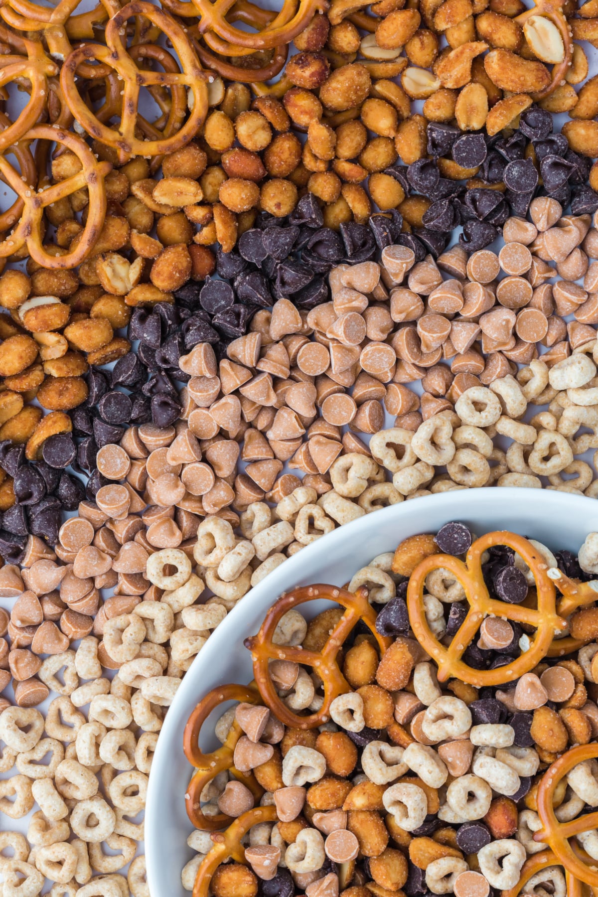 A bowlful of snack mix beside rows of each ingredient.