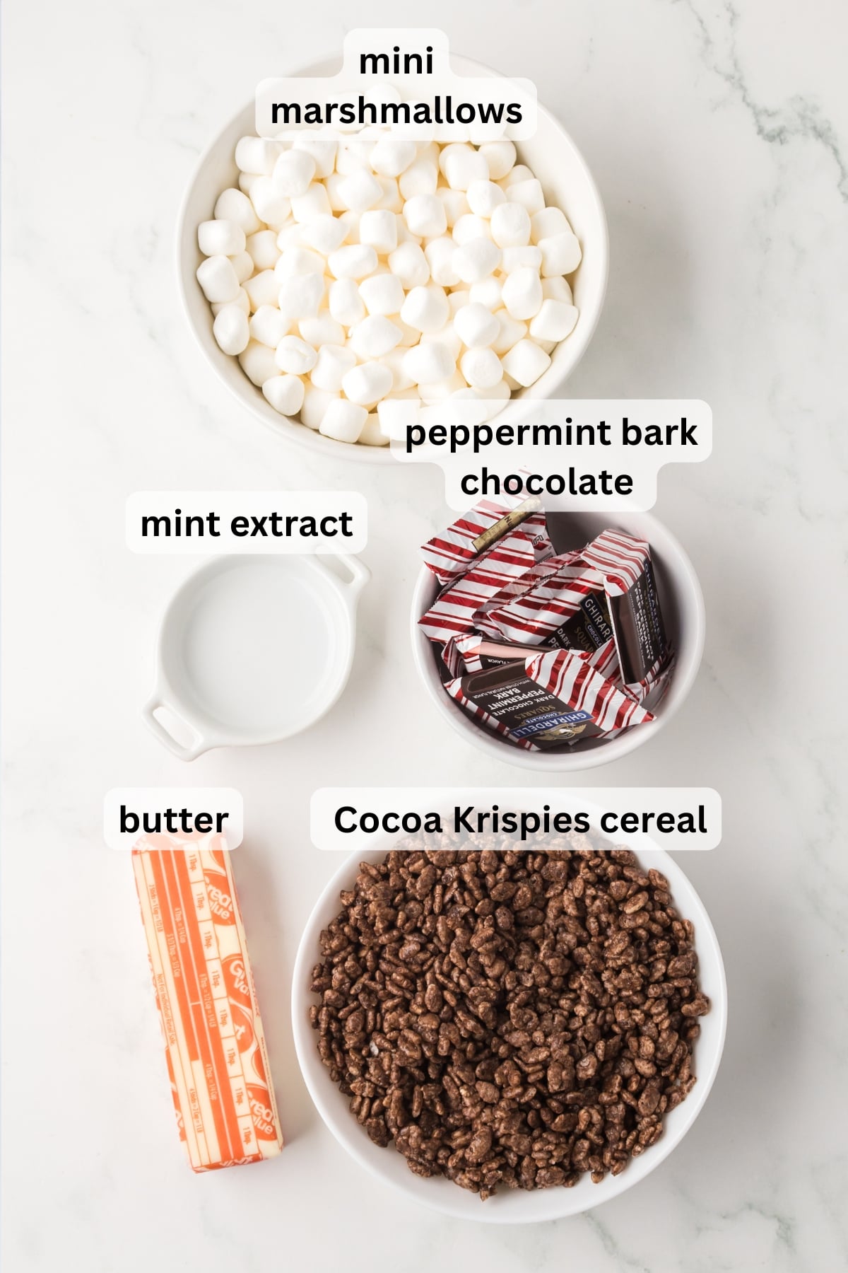 Ingredients for Peppermint Bark Rice Krispie Treats arranged in bowls on a table.