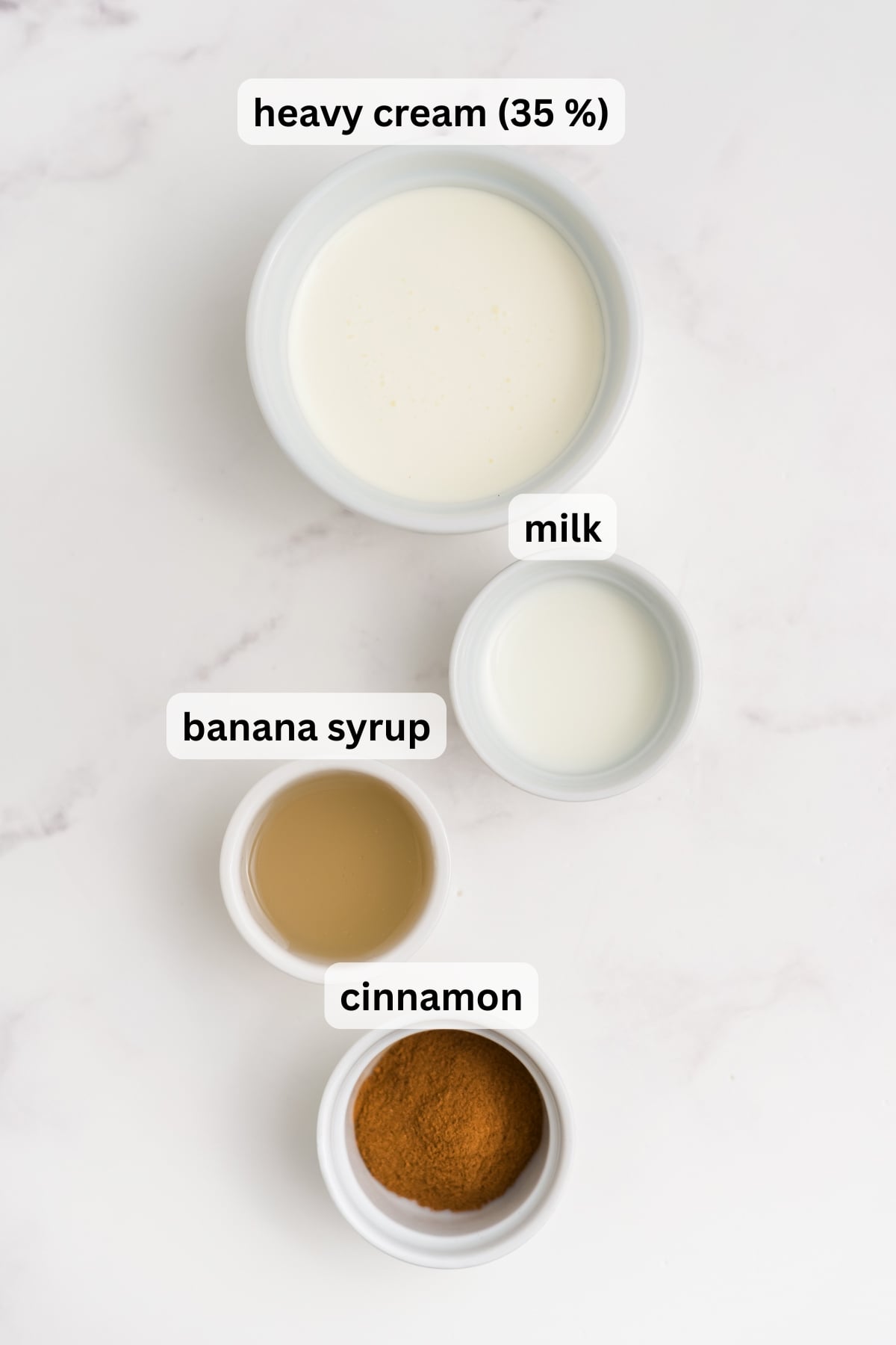 All of the ingredients needed to make banana cold foam in bowls on a table.