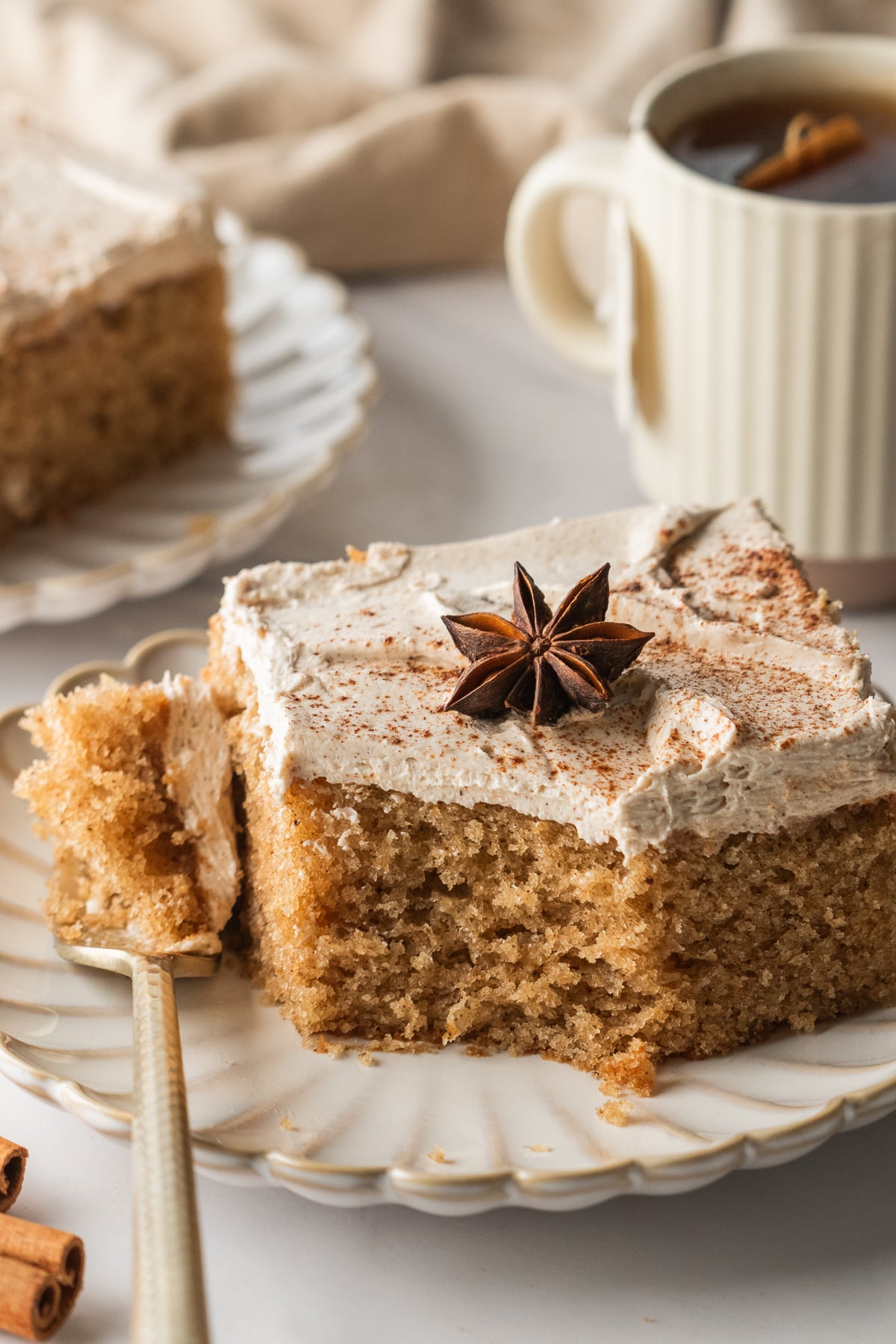 A slice of cake on a plate missing a bite with a fork.