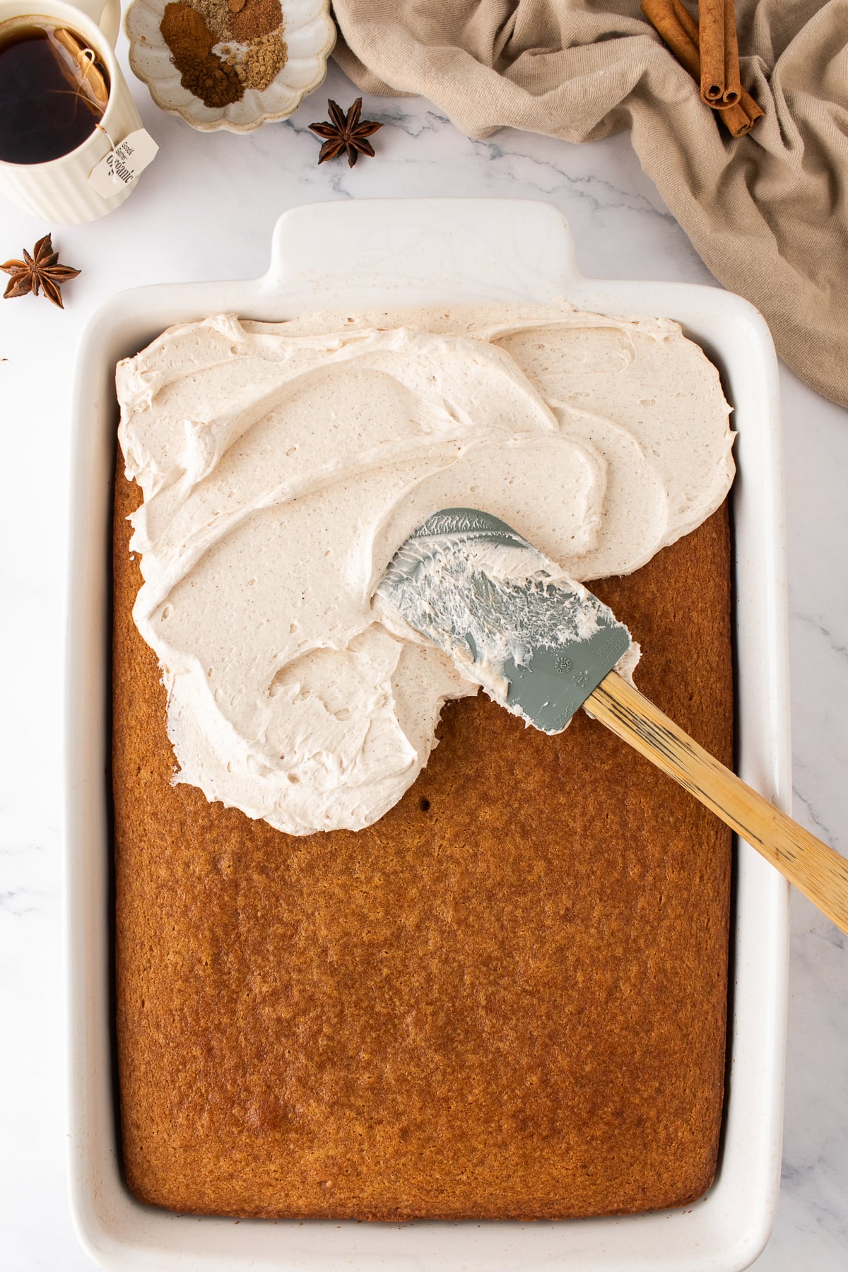 Cake being frosted with buttercream and swirled with a spatula.