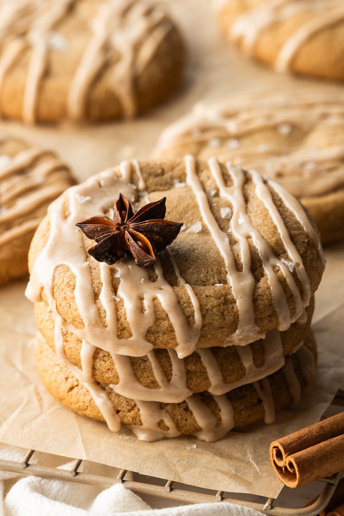 A stack of cookies topped with a star anise on a parchment covered rack.