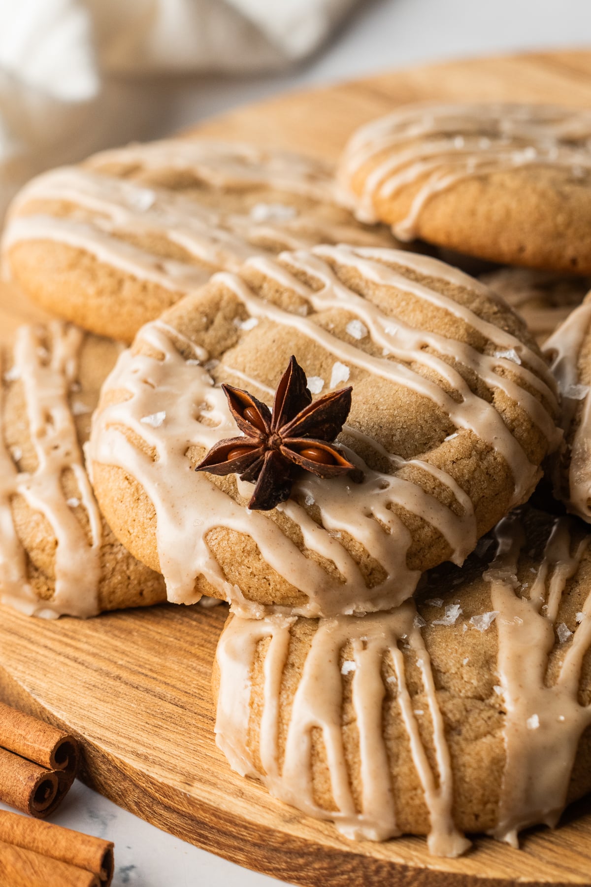 Cookies piled on a wooden serving board with a star anise on top.