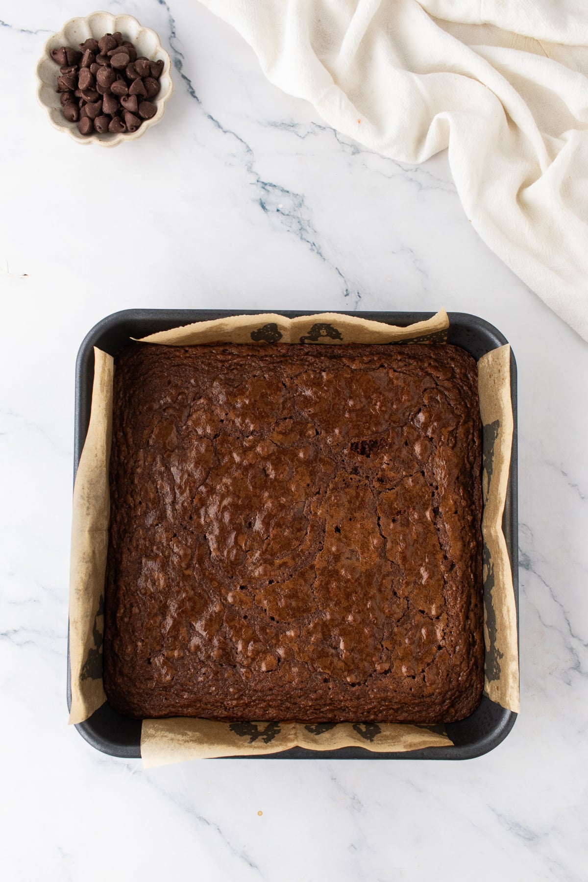 Baked chocolate brownie layer cooling in a square metal pan