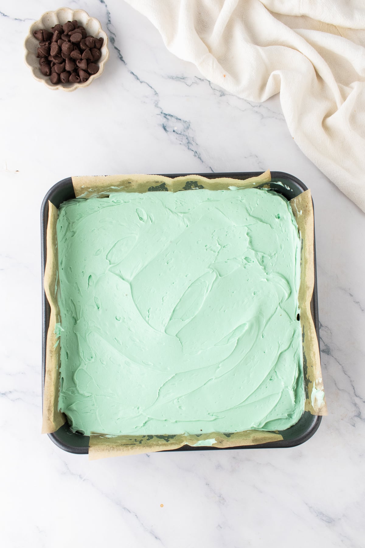 Green mint frosting spread evenly over the cooled brownie layer