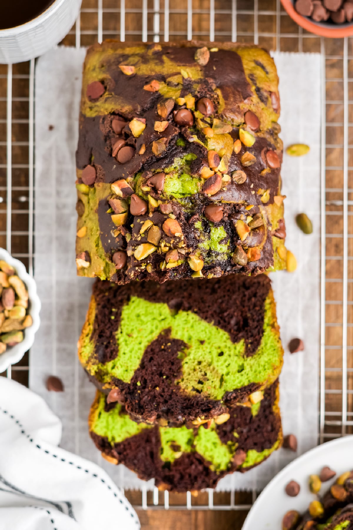 Loaf on a platter with two slices cut showing the pistachio and chocolate swirl.
