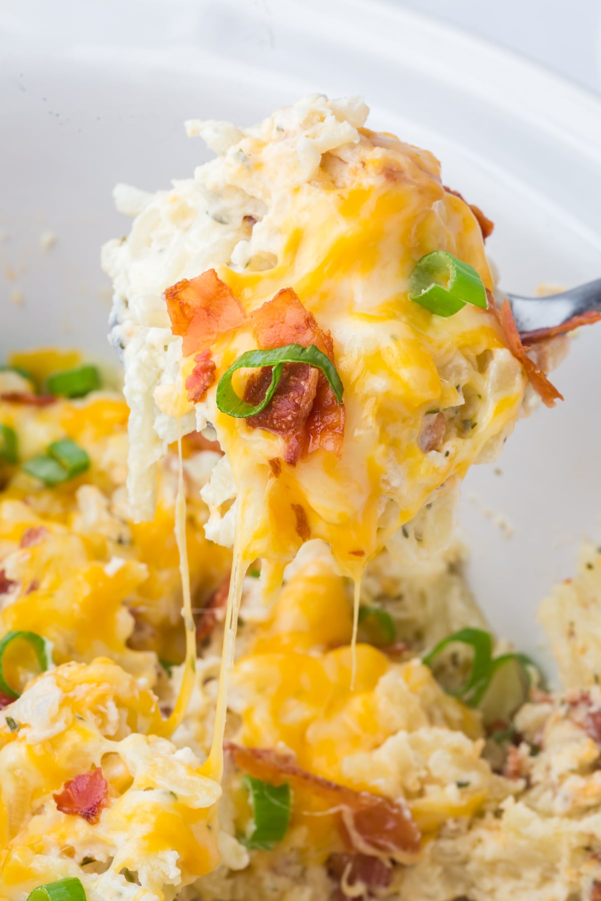 A spoonful of potatoes being lifted out of the crockpot.