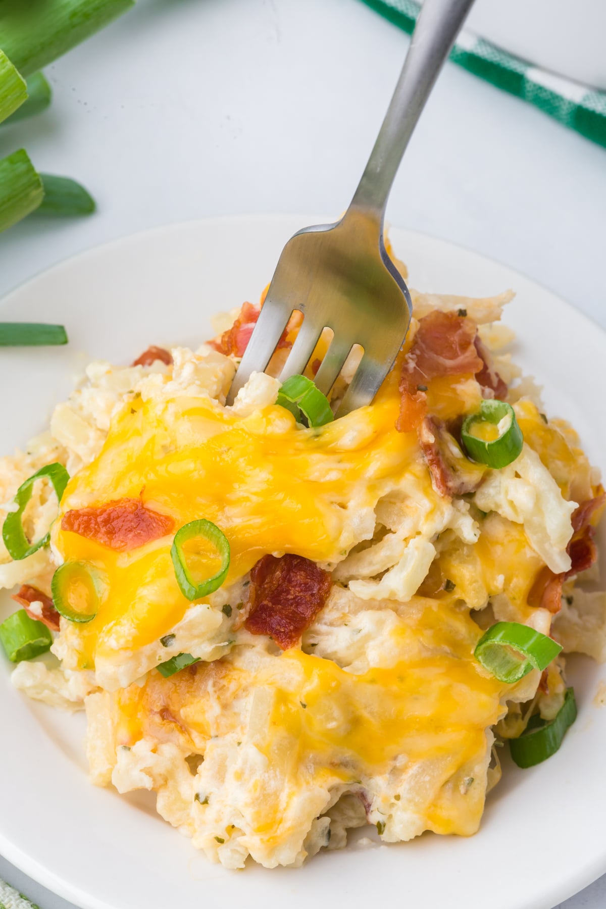A serving of potatoes on a plate with a fork pressed into the potatoes.