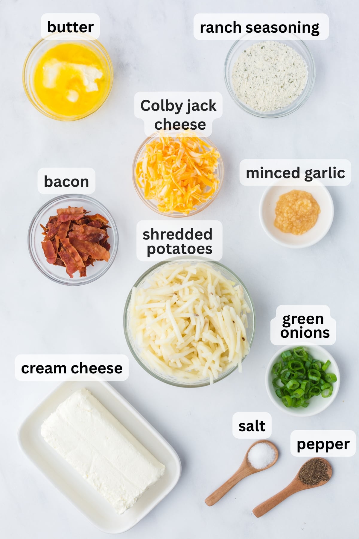 All of the ingredients needed for crockpot ranch potatoes with bacon, cheese, ranch, and russet potatoes in bowls on a table.