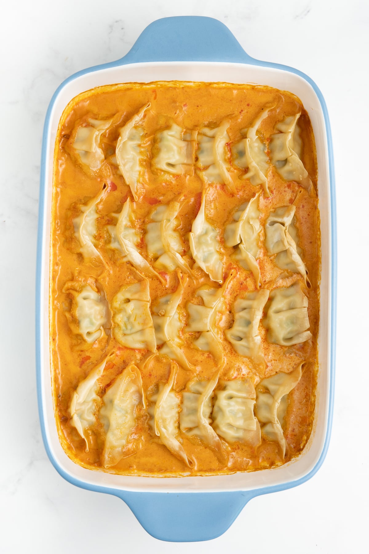 Baked dumplings bubbling in creamy coconut red curry sauce after the foil is removed.