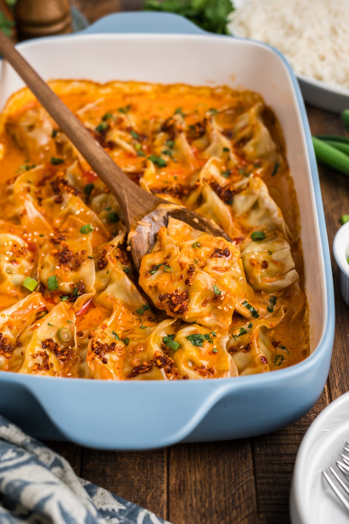 A wooden spoon lifting some freshly baked dumplings out of the casserole dish.