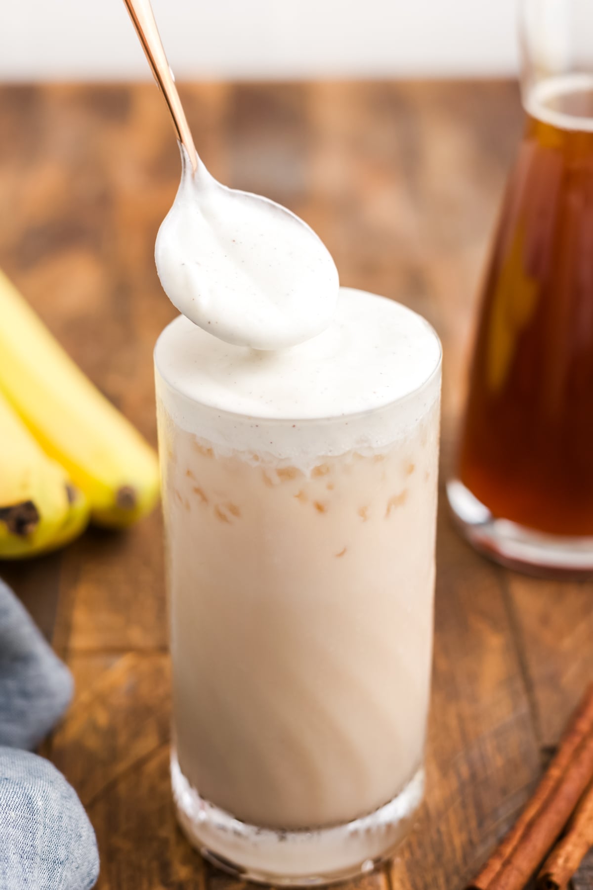 Creamy cold foam being added to an iced chai.