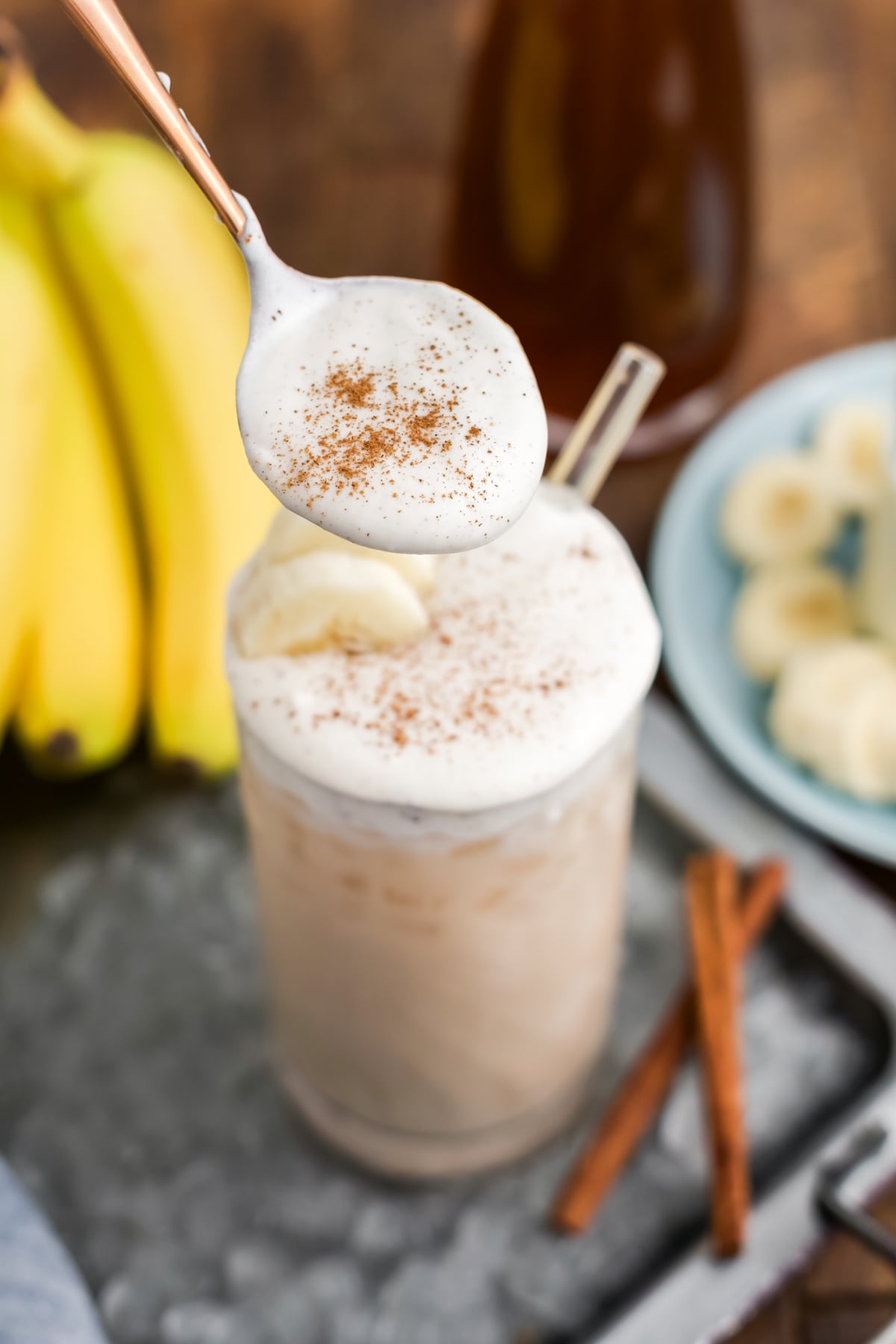 A spoonful of cold foam above the glass with a sprinkling of cinnamon on top.