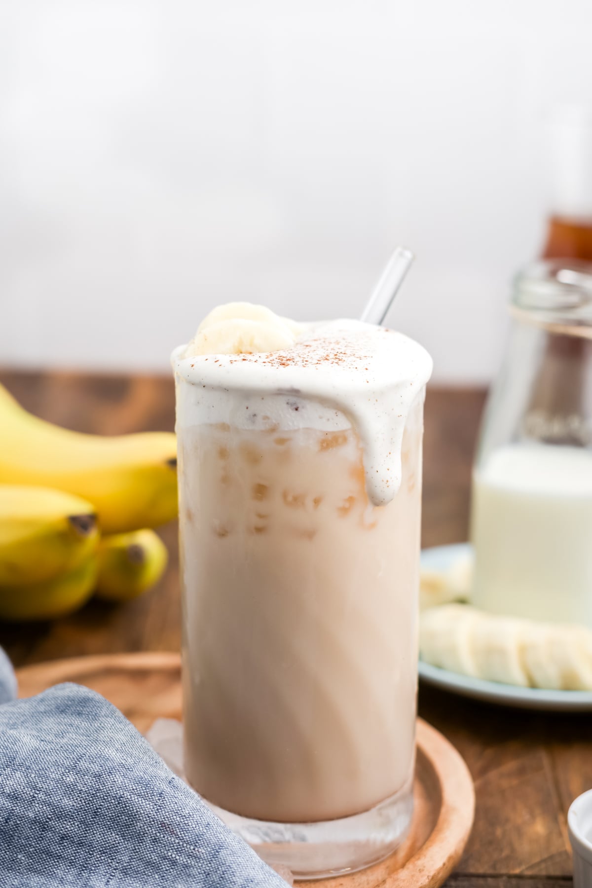 Latte topped with thick banana cold foam dripping down side of glass.