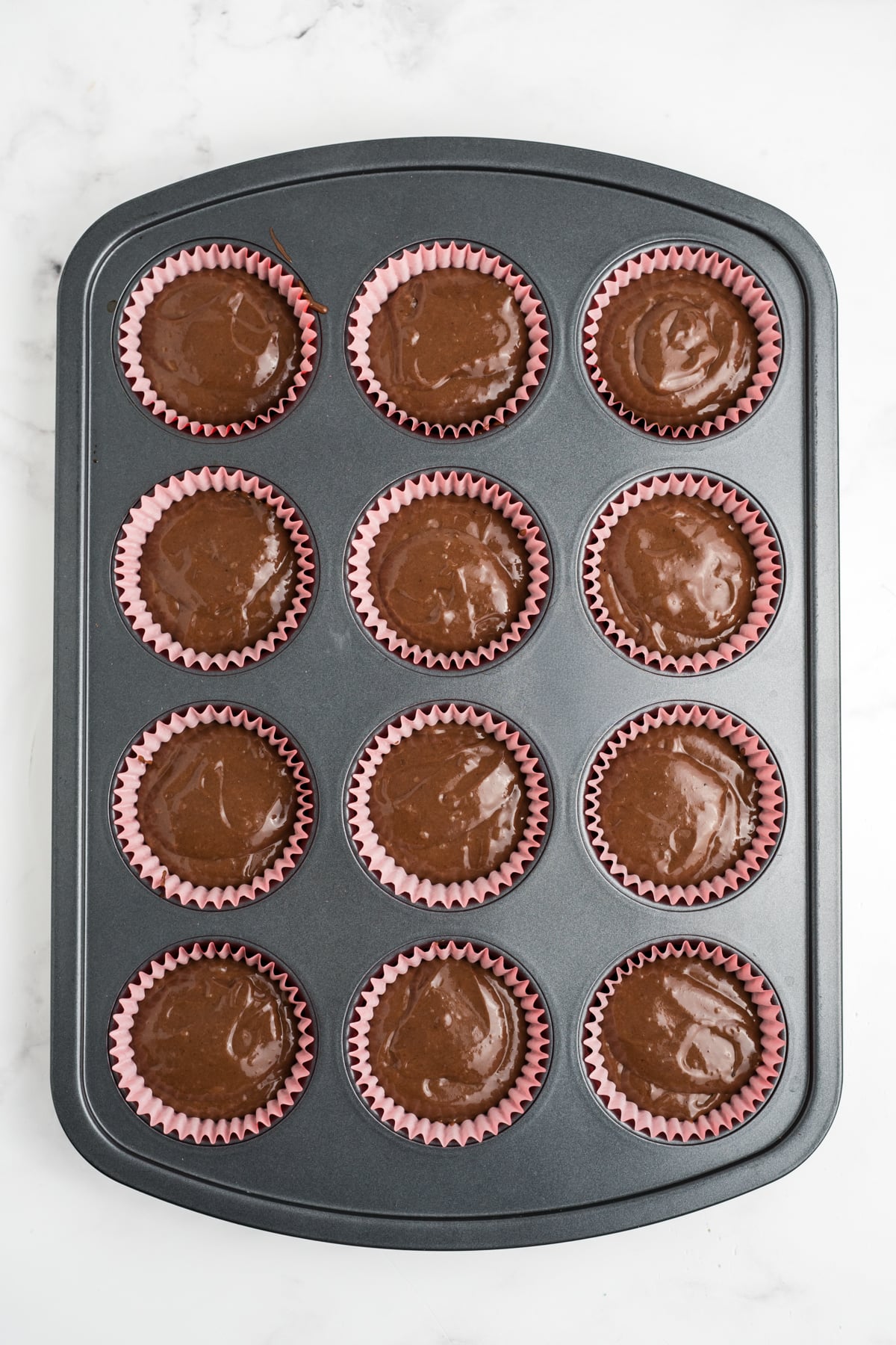Cupcake batter filling the liners about ยพ full.