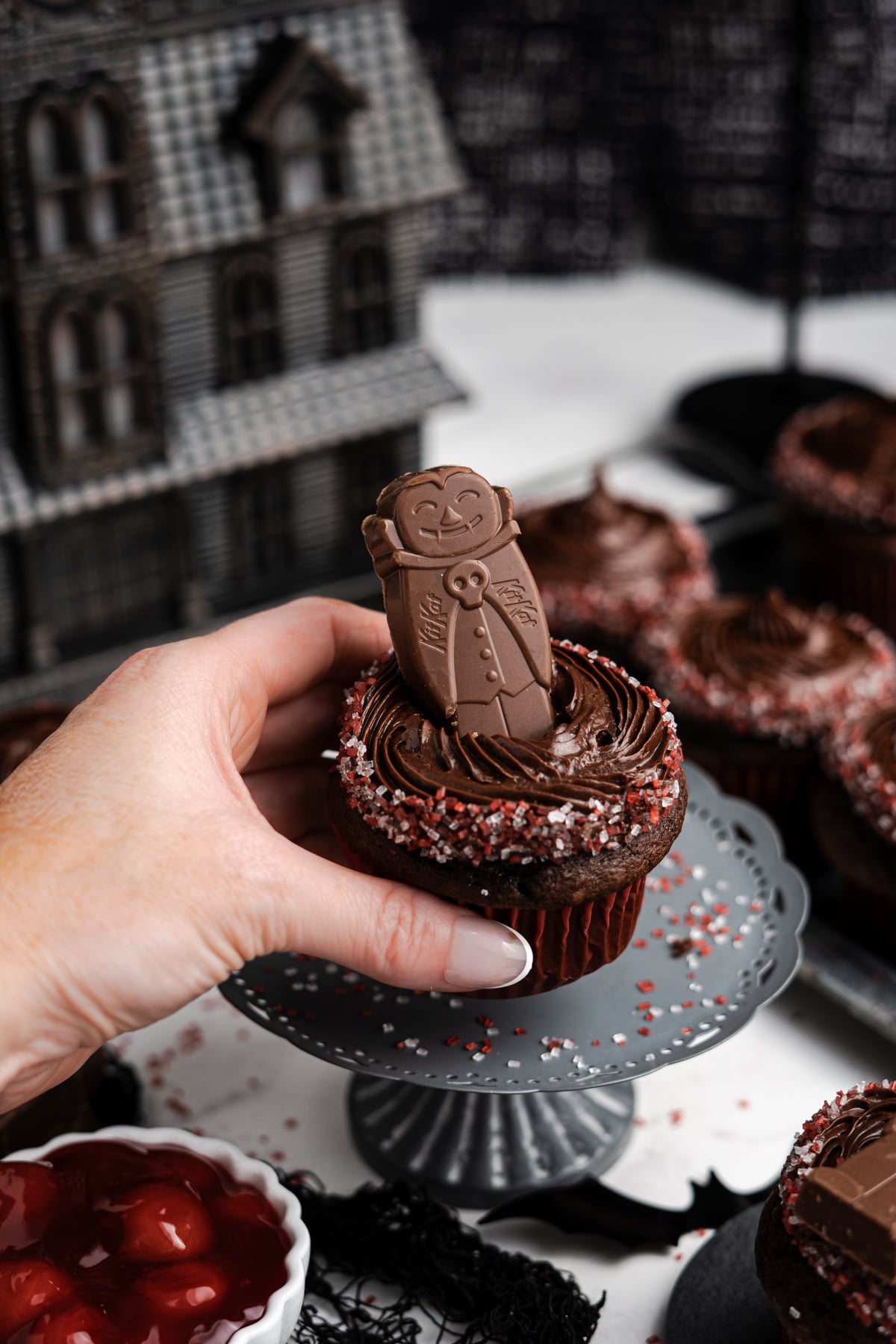 A hand placing a cupcake on a pedestal.