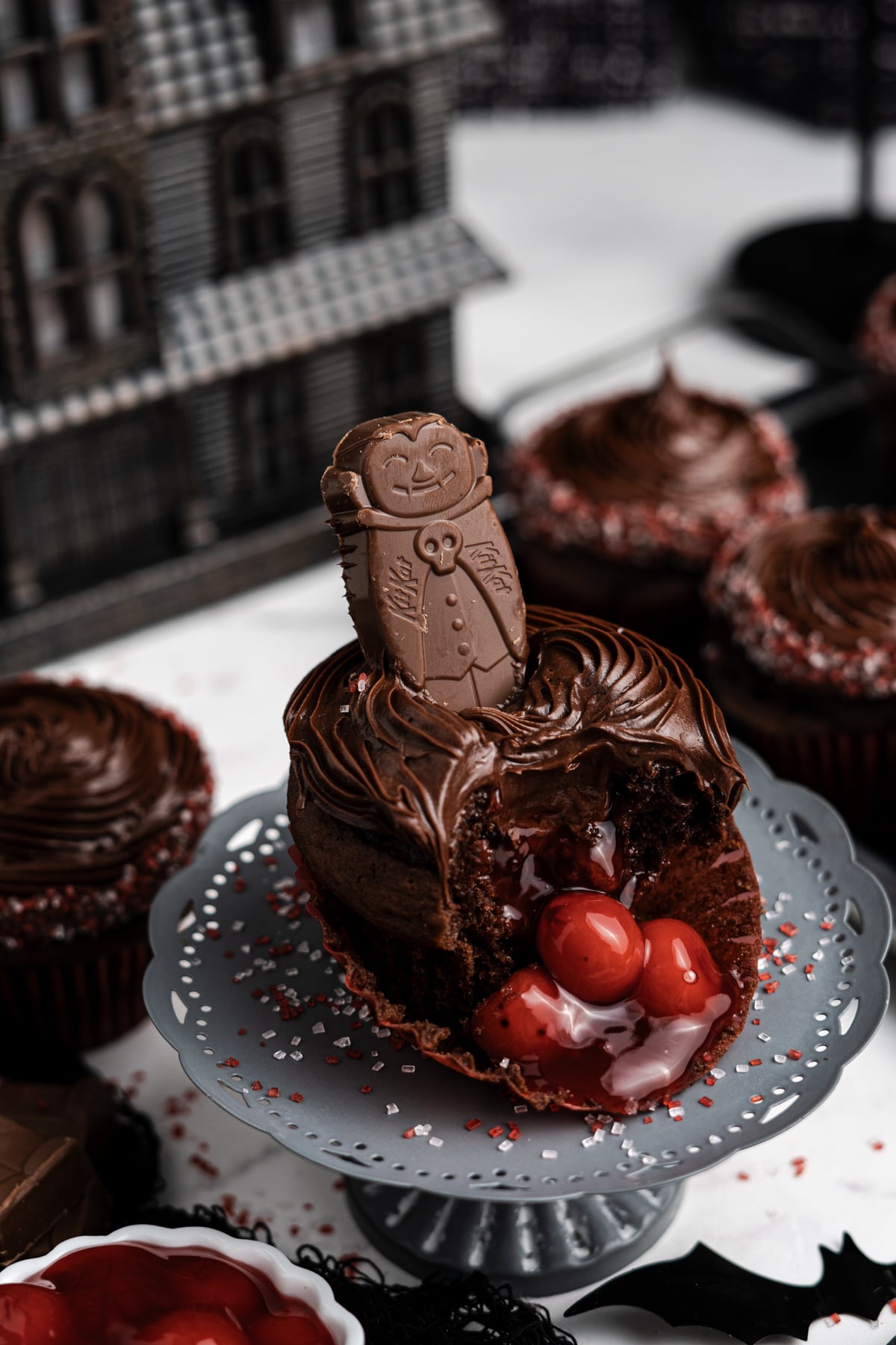 Cupcakes on a table with one broken open showing the cherries inside.