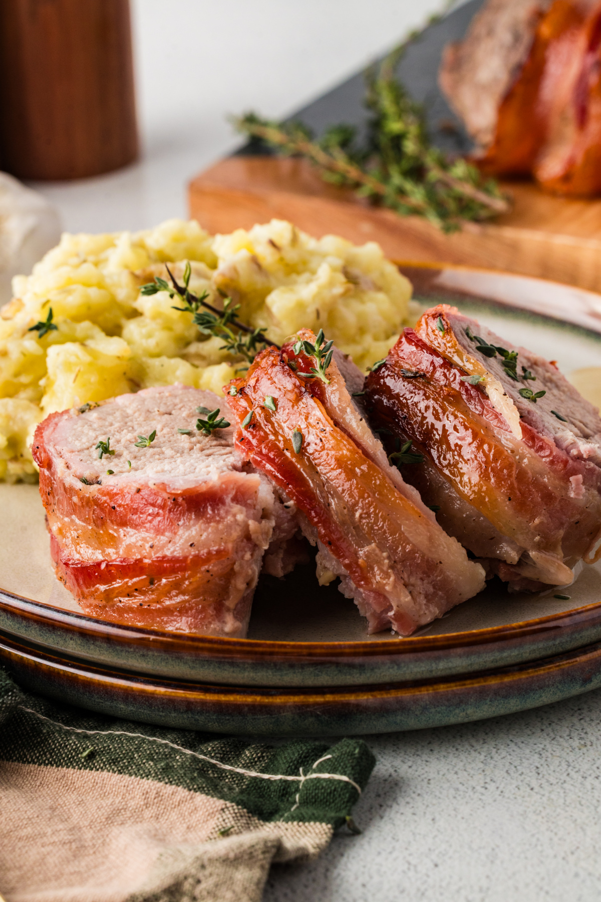Sliced pork tenderloin served on a plate with mashed potatoes.
