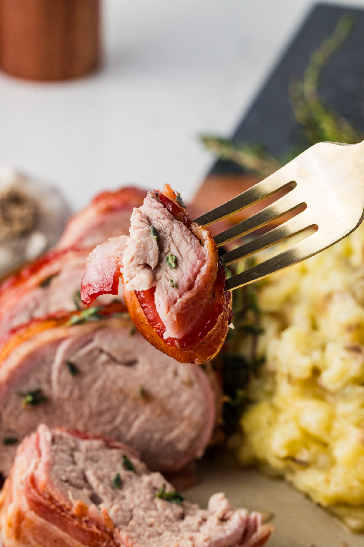 A forkful of pork tenderloin held in the air.