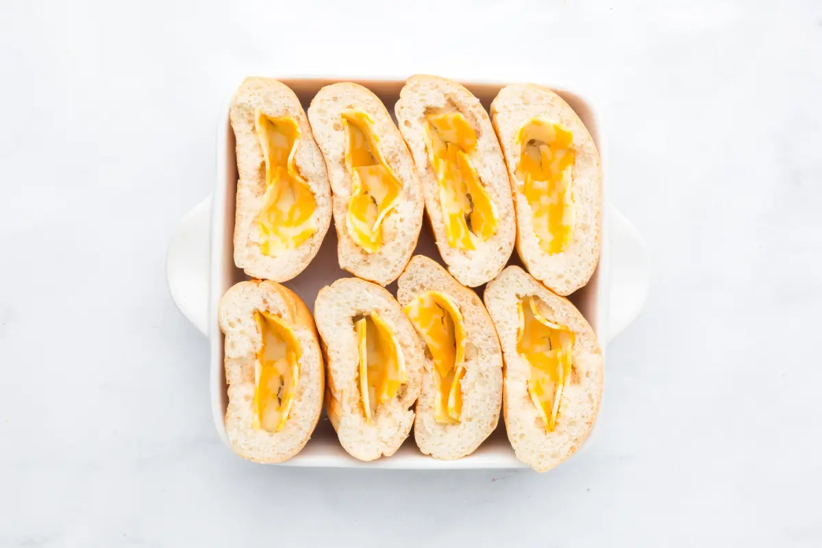 Cut, toasted buns with a slice of cheese placed inside.