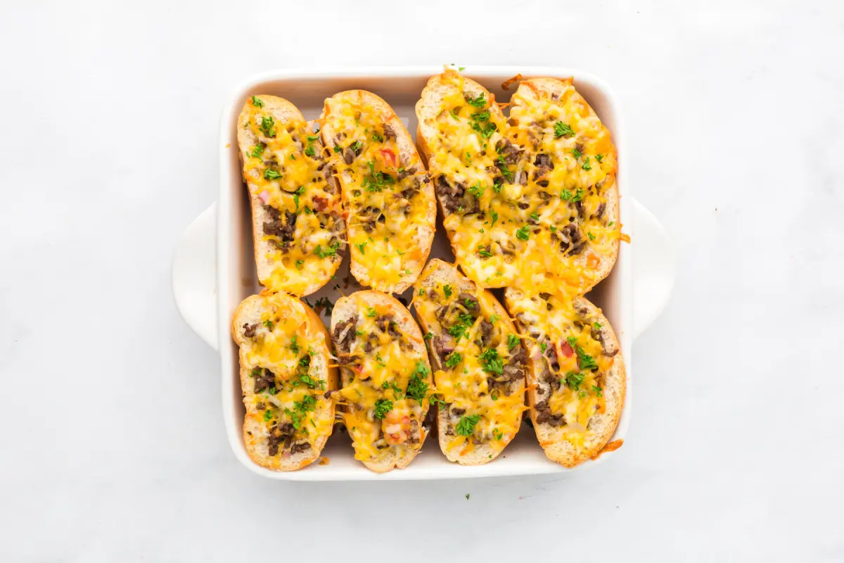 Baked buns covered with melted cheese and and chopped parsley.