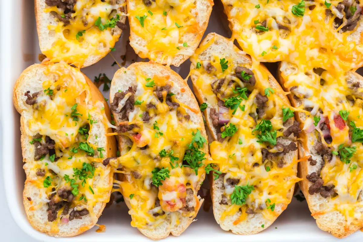 Freshly baked burger rolls in pan with a sprinkling of parsley on top.