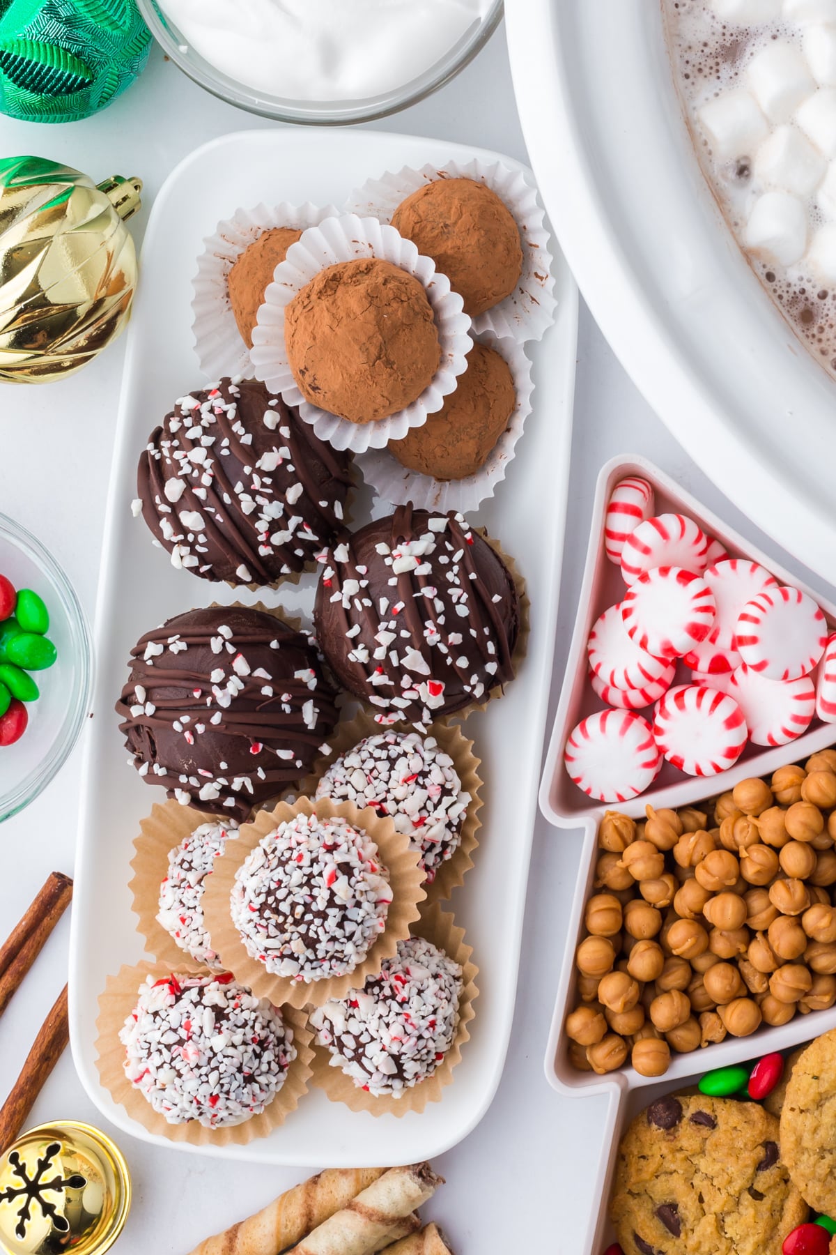 Hot cocoa bar toppings and treats arranged in decorative bowls on a table.