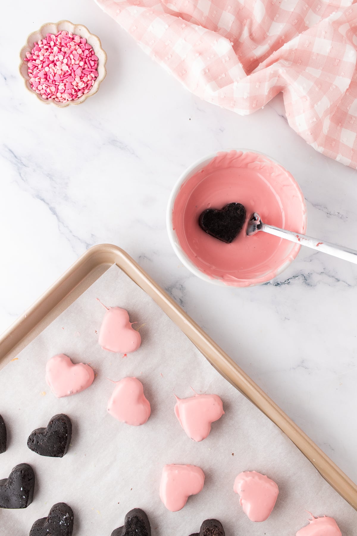Chilled Oreo Heart being dipped into melted pink candy coating with a fork.
