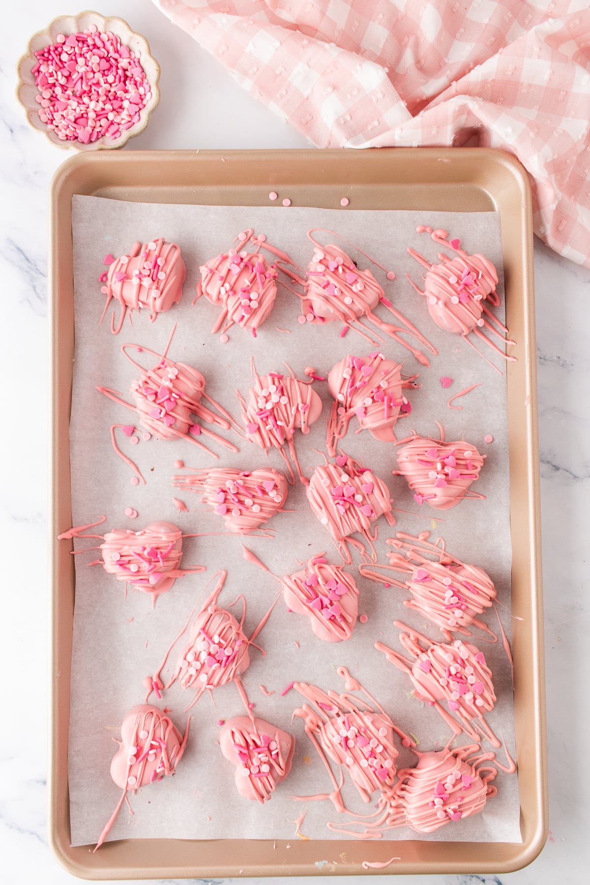 Pink hearts decorated with candy drizzle and Valentine's Day sprinkles.