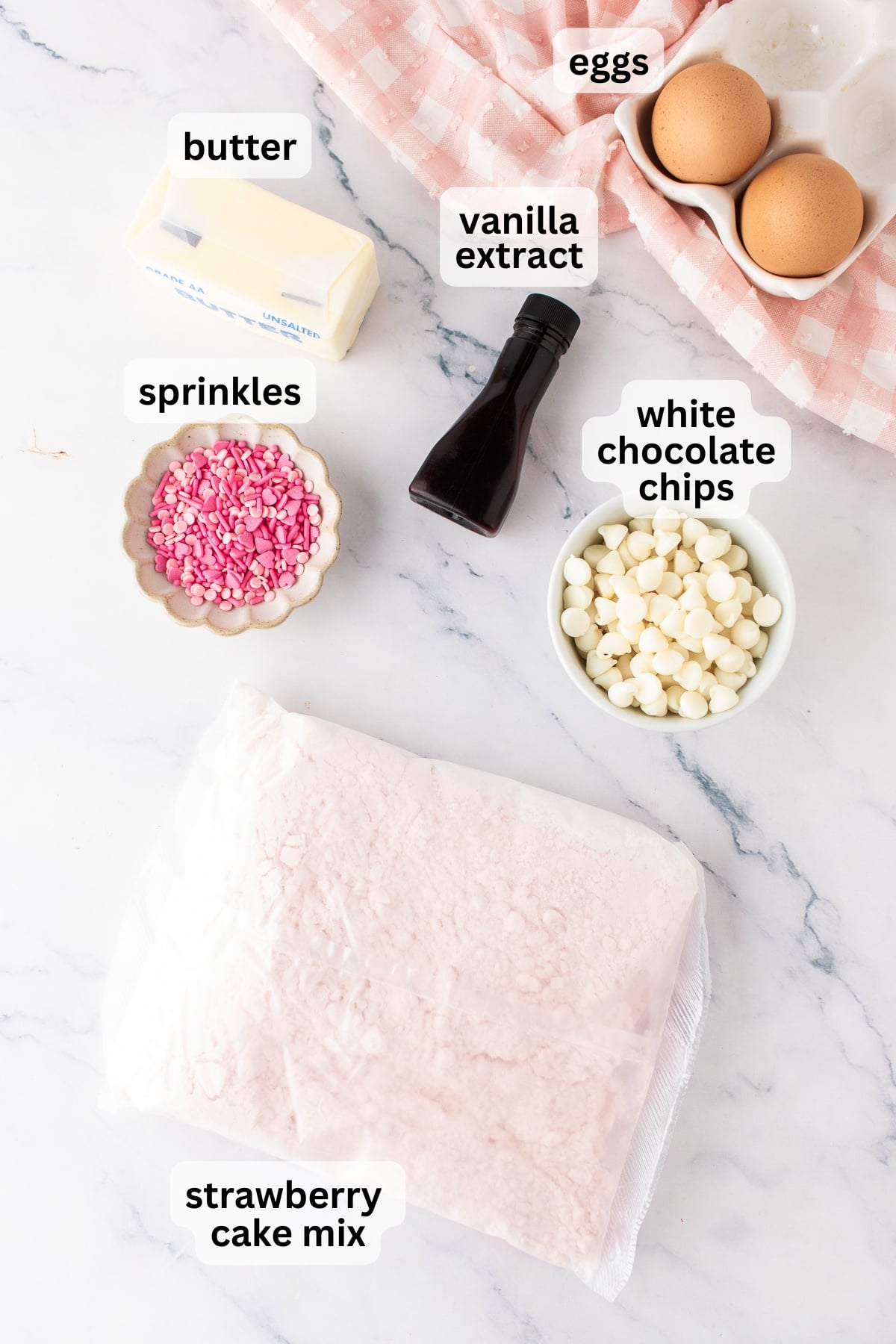 All of the ingredients needed to make pink velvet cookies in bowls on a table.