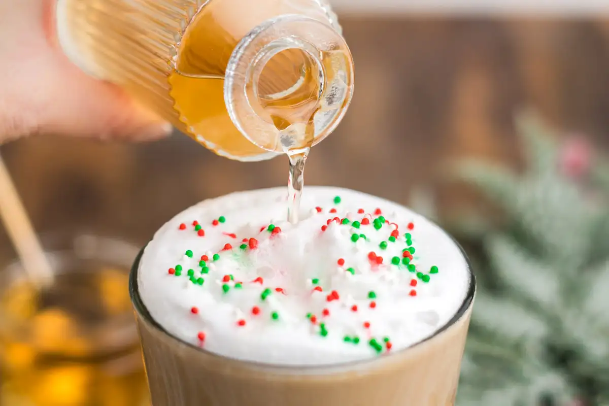 Sugar cookie syrup being poured into a cold foam topped sugar cookie Frappuccino.