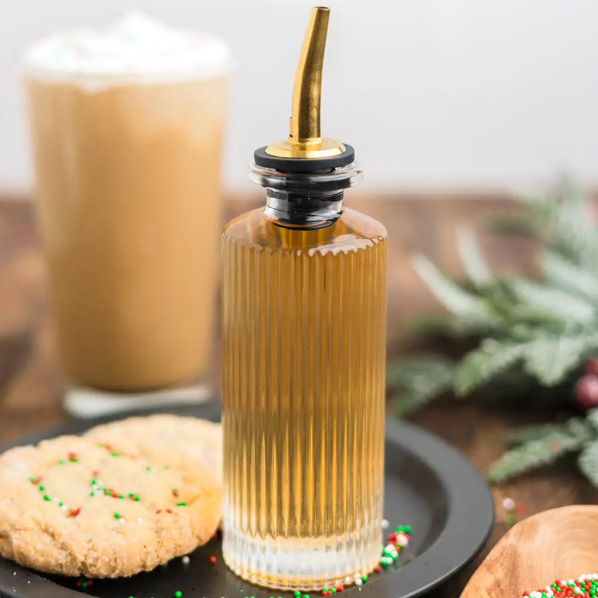 A glass syrup dispenser filled with homemade sugar cookie syrup.