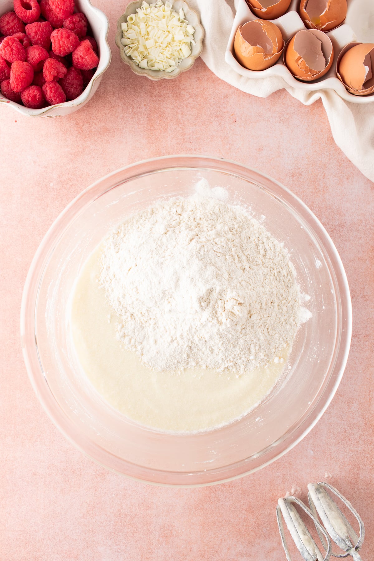 Dry ingredients added to blended wet ingredients in a mixing bowl.