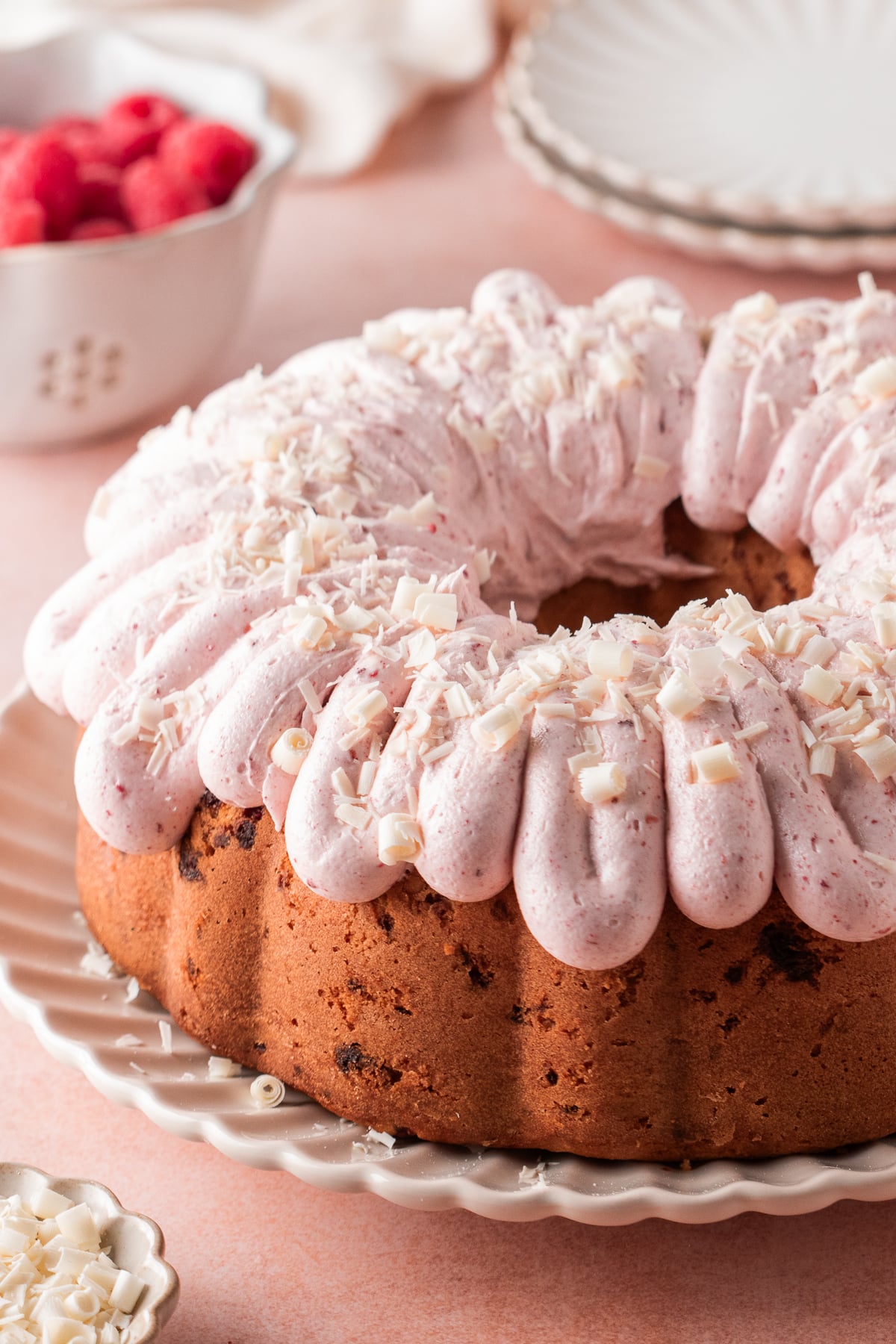 Frosted white chocolate raspberry Bundt cake on a plate.