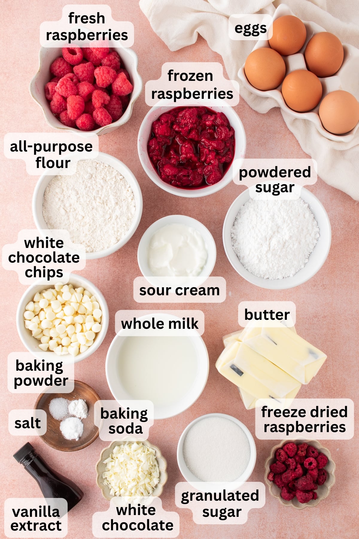 All of the ingredients needed to make white chocolate raspberry cake in bowls on a table.