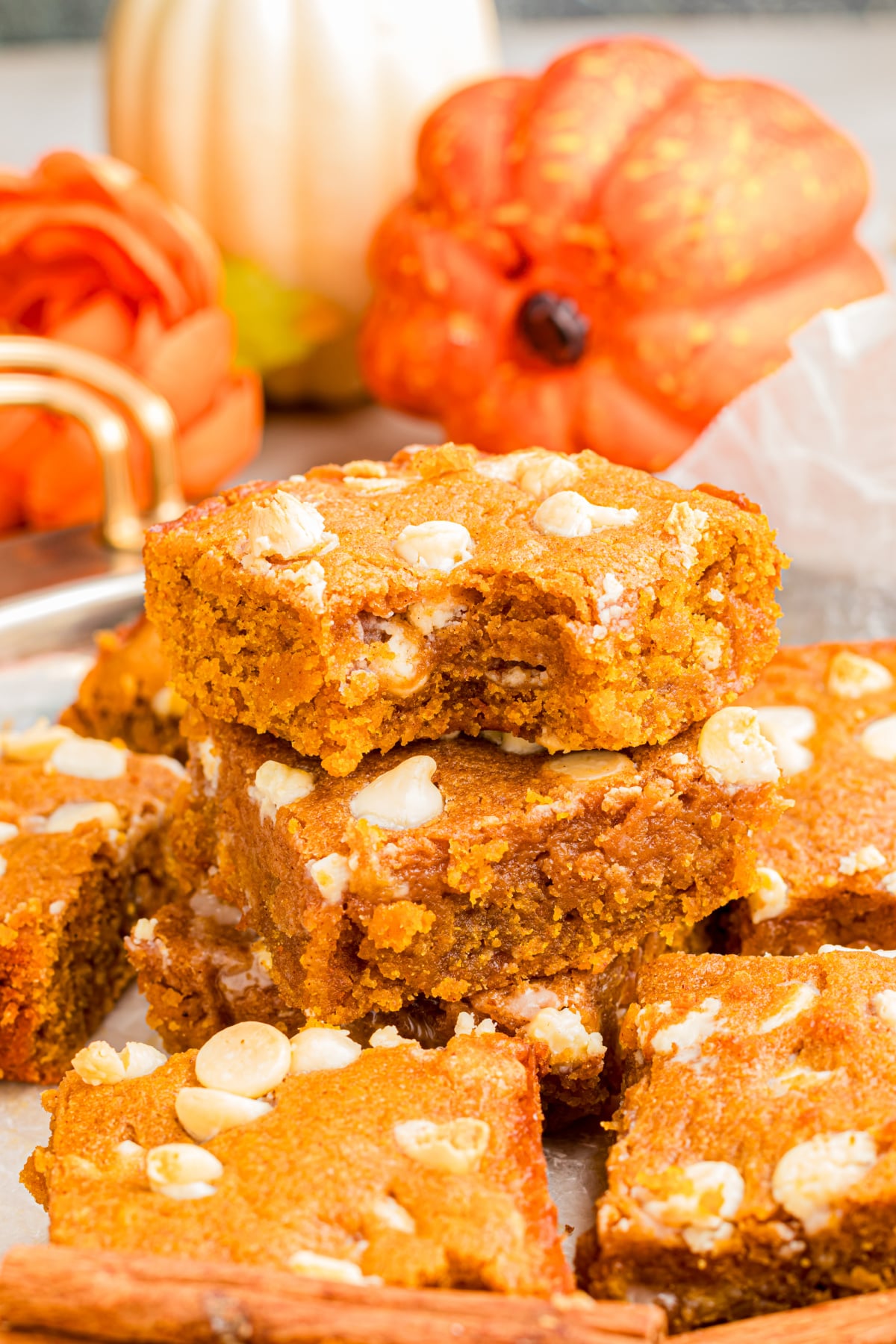 A pile of blondies on a plate with the top one missing a bite.