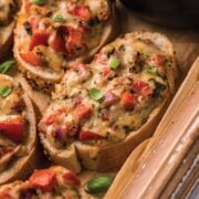 Closeup photo of Bruschetta with cheese placed on a wooden tray.